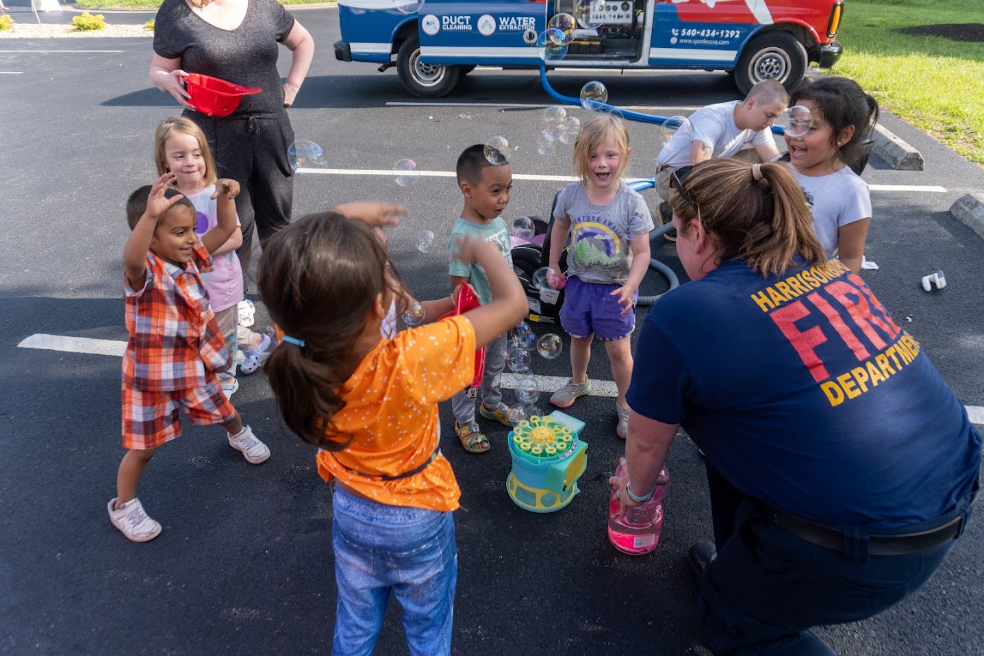 Firefighter plays bubbles and games with children while they get their car seats checked. 