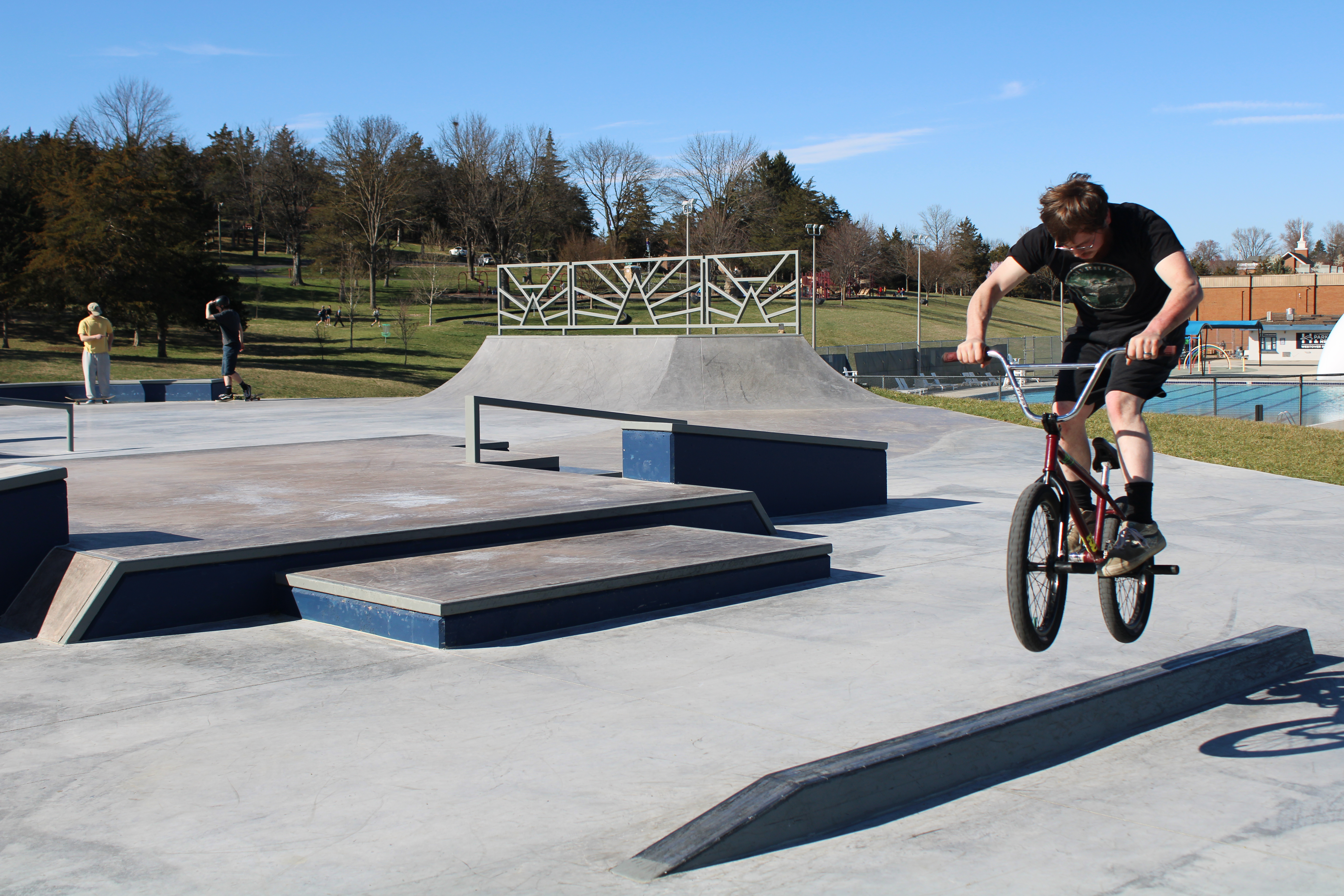 Man on a bmx bike jumping over a square rail.