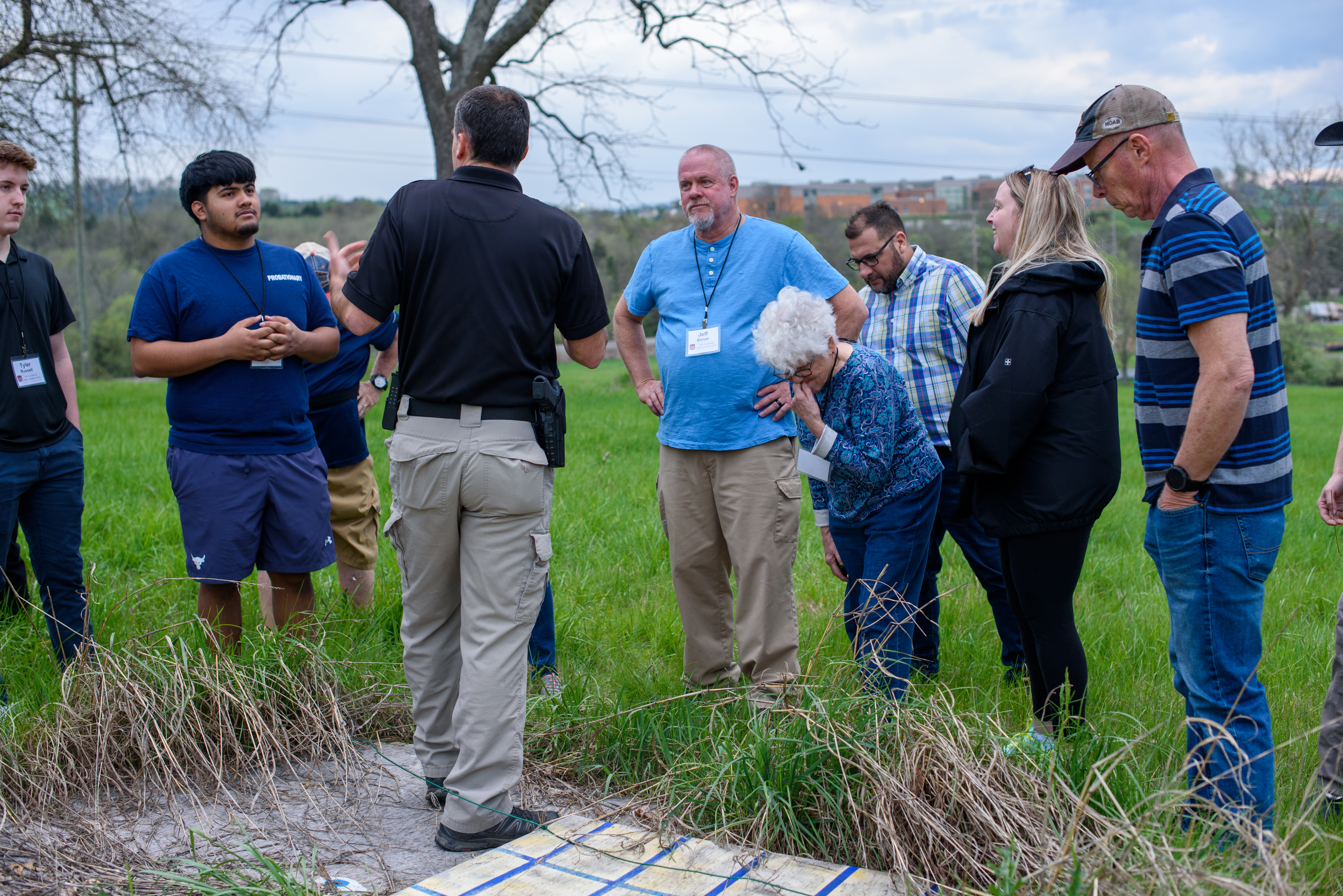 A Police Detective speaking with a group of individials outside